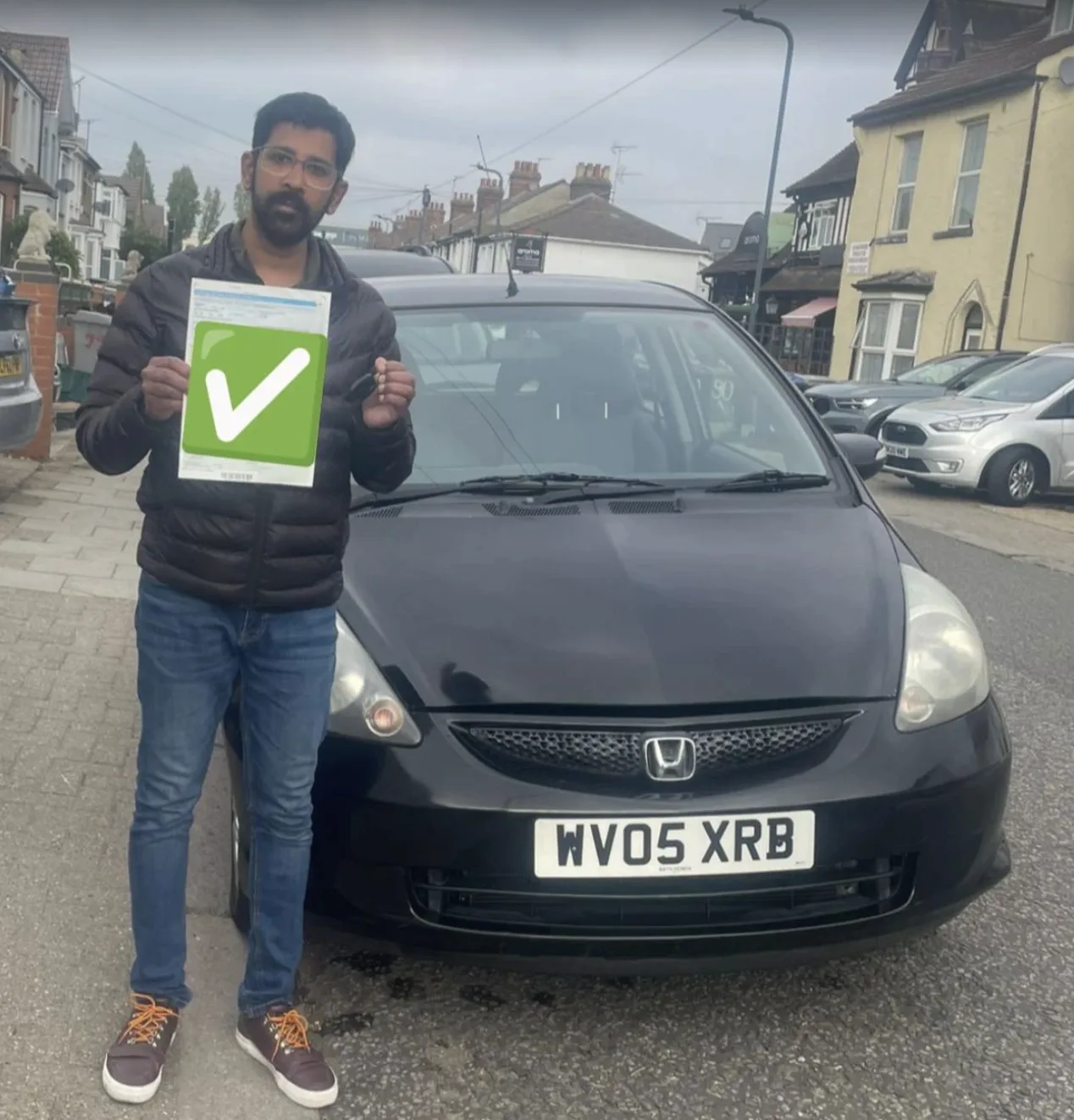 Successful driving test candidate holding pass certificate outside DVSA test centre in Pinner area, North London