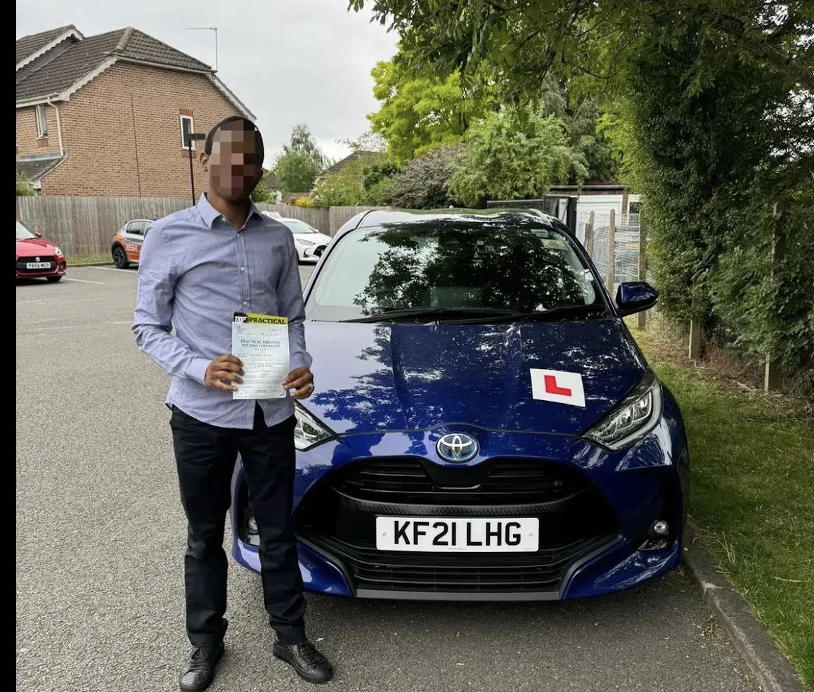 Successful driving test candidate holding pass certificate outside DVSA test centre in Pinner area, North London