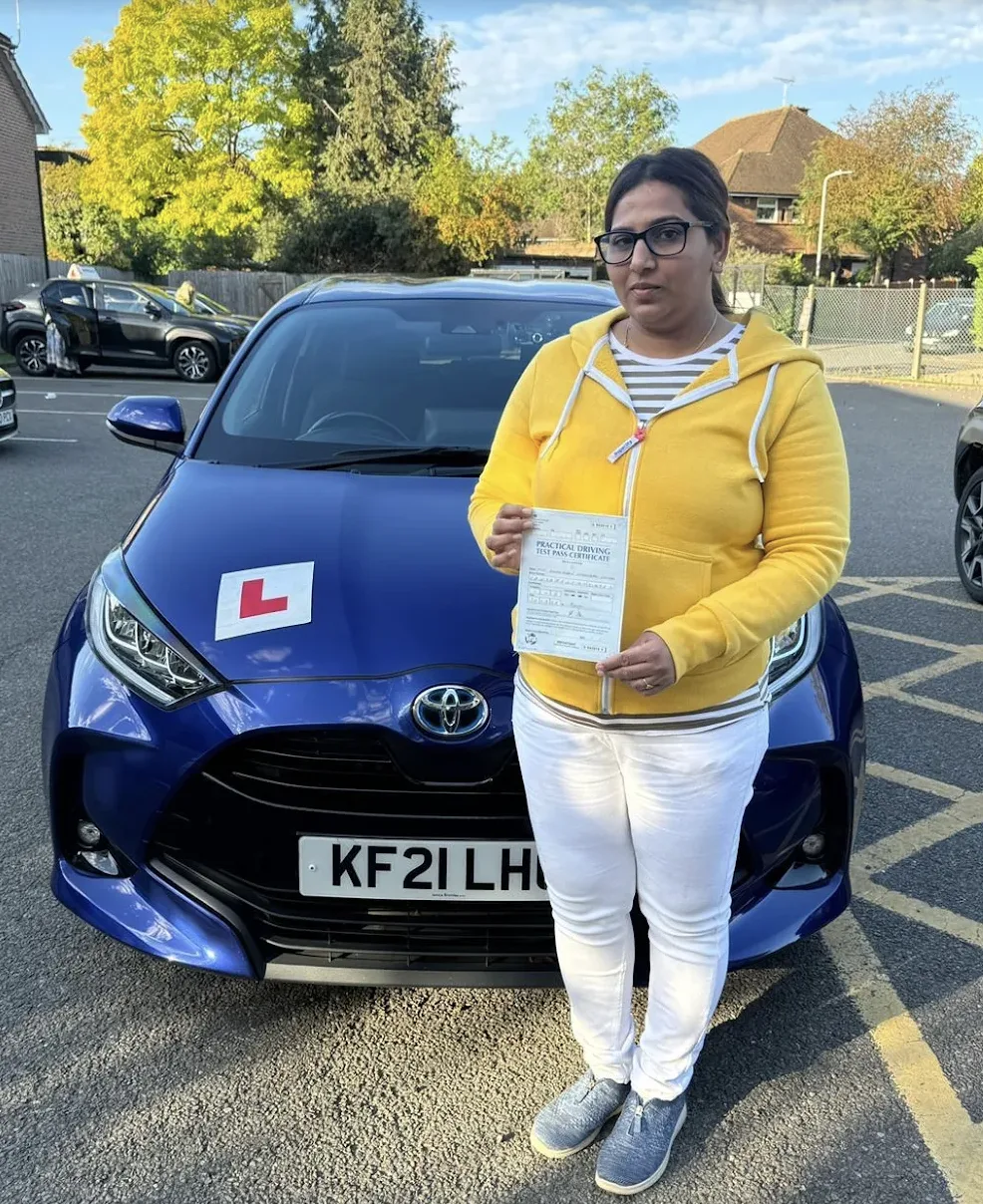 Successful driving test candidate holding pass certificate outside DVSA test centre in Pinner area, North London