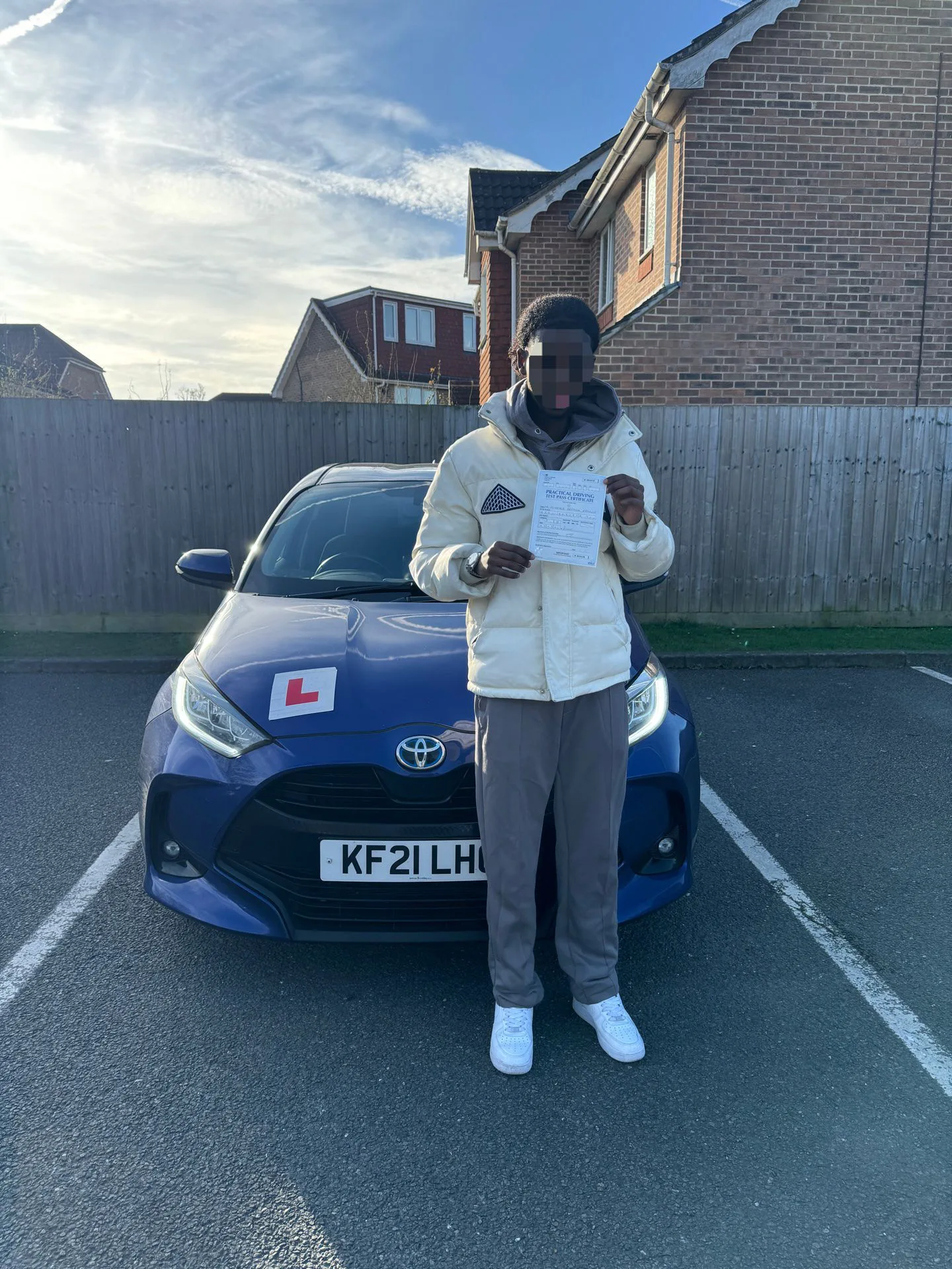 Successful driving test candidate holding pass certificate outside DVSA test centre in Pinner area, North London