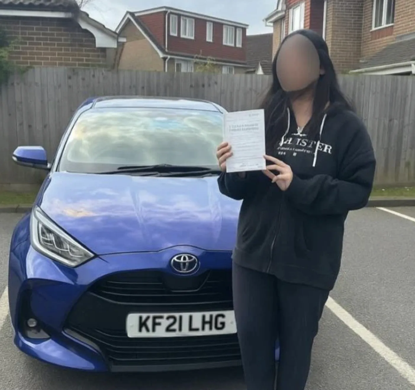 Successful driving test candidate holding pass certificate outside DVSA test centre in Pinner area, North London